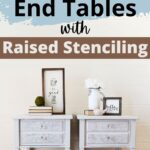 Two white end tables with raised stencil fronts, decorated with framed art, books, and vases on top.