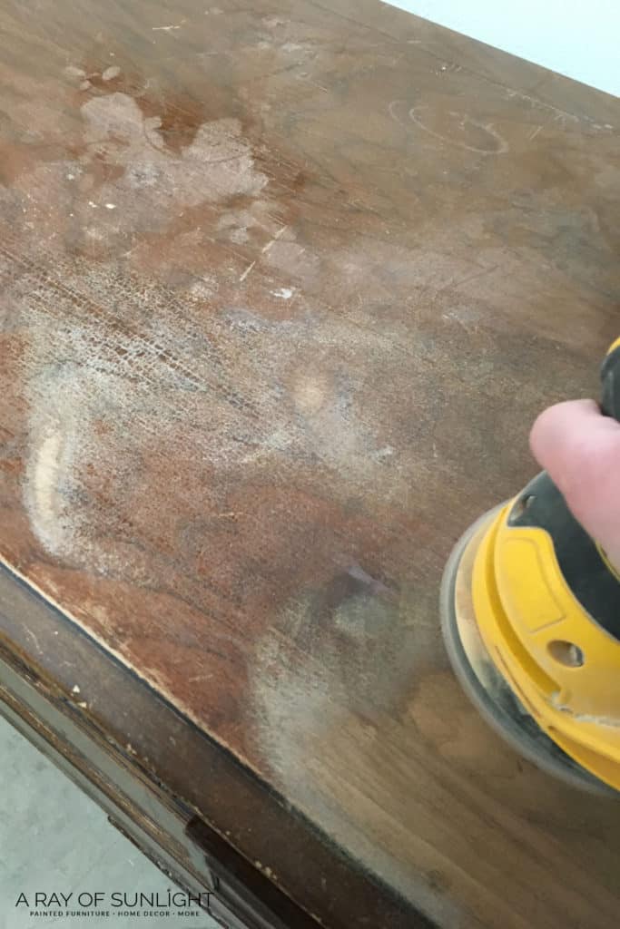 Close view of sanding the wood top of a dresser
