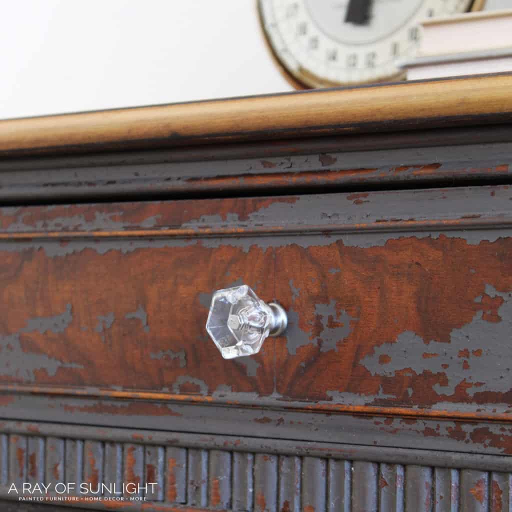 Close view of a clear hardware knob on a chippy milk painted dresser