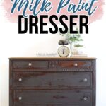 A chippy gray dresser with milk paint finish, topped with a plant and vintage scale, against a white wall.
