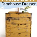 Yellow distressed farmhouse dresser with black knobs, decor on top, and a sign
