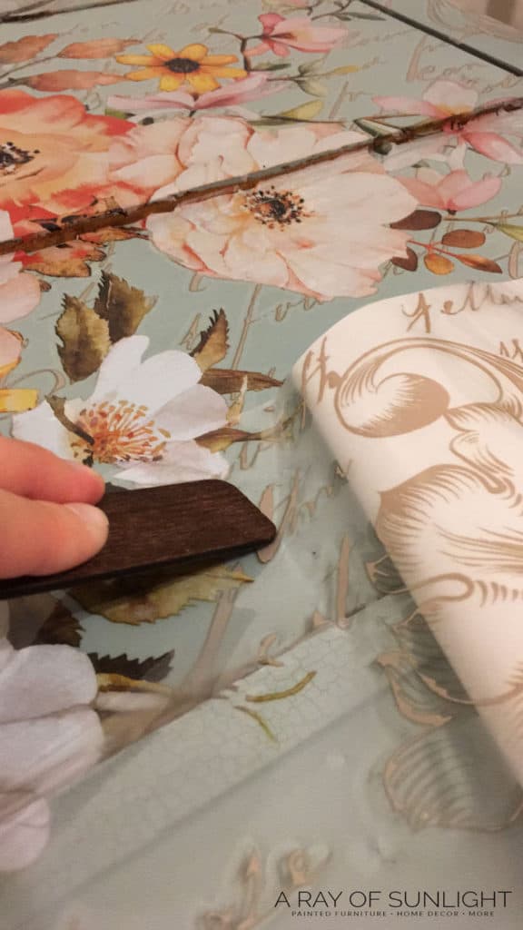 Rubbing the floral transfer onto the dresser with a wooden stick