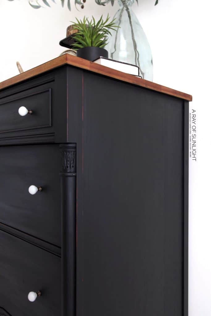 Right side view of black painted dresser with wood top and white knobs