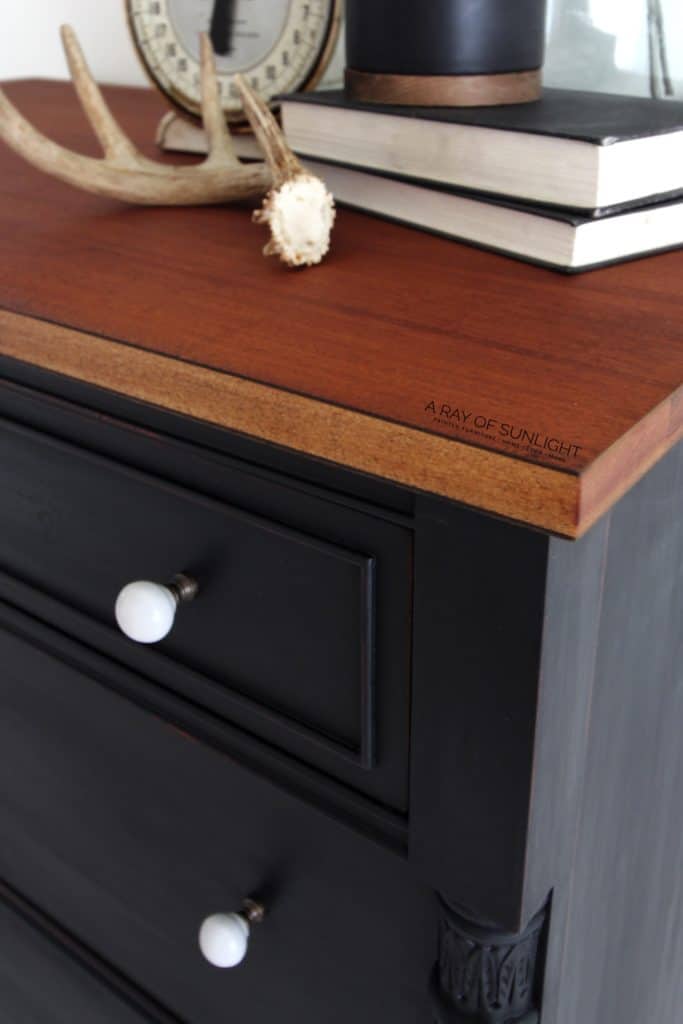 closeup of wood top and black painted dresser with white knobs