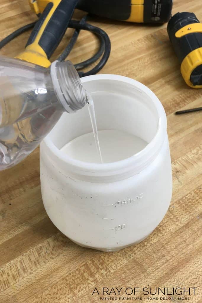 pouring water into chalk paint in paint sprayer container
