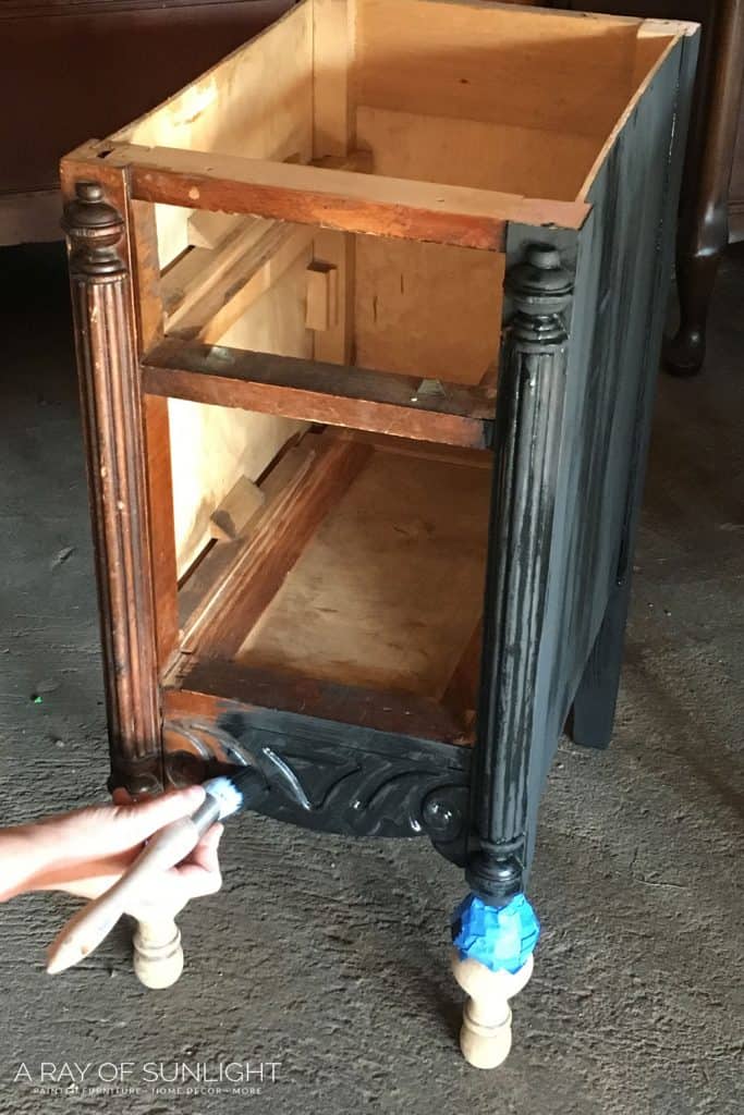 using a paintbrush to paint nightstands black