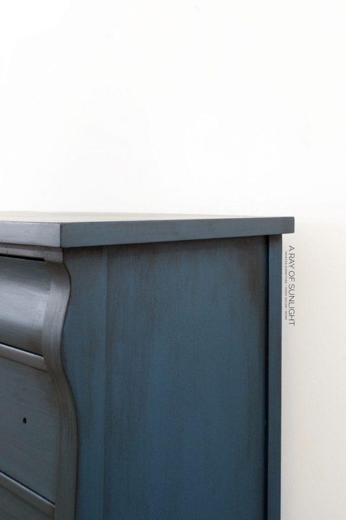 Side view of navy blue dresser with dark glaze