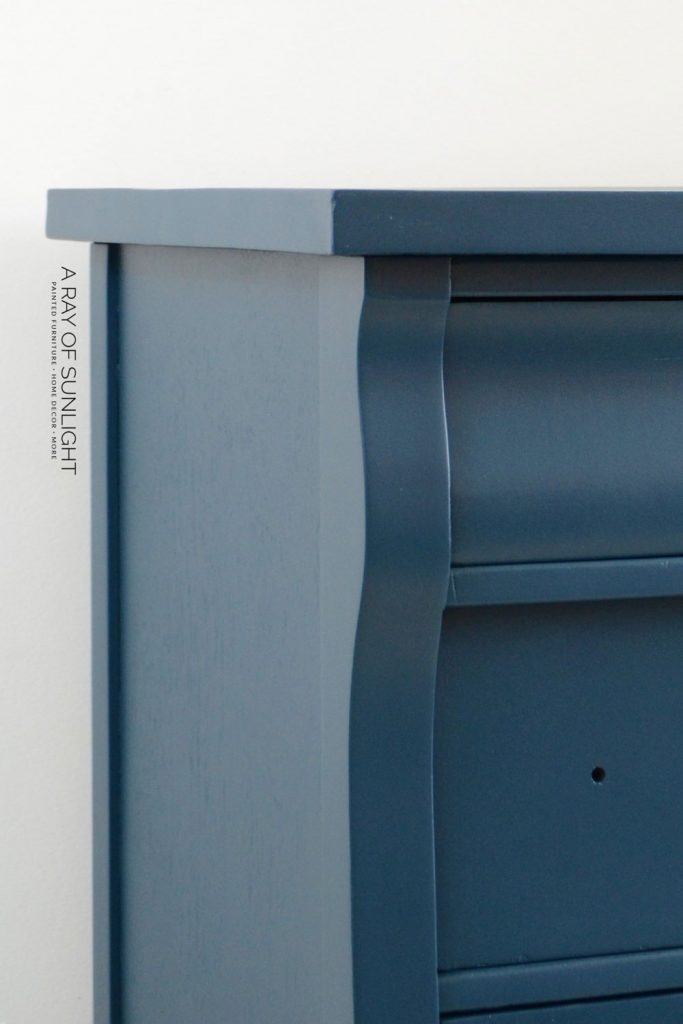 Closeup of tall navy blue painted dresser with no hardware