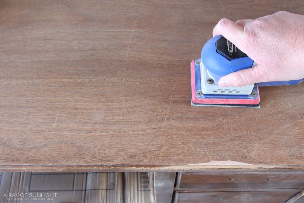 sanding top of wood desk with sander