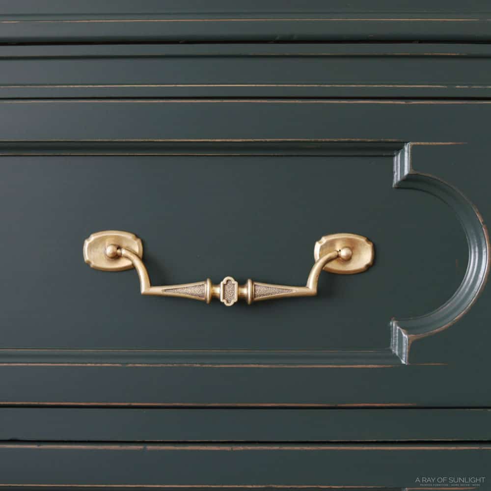 closeup of cleaned brass hardware on green dresser