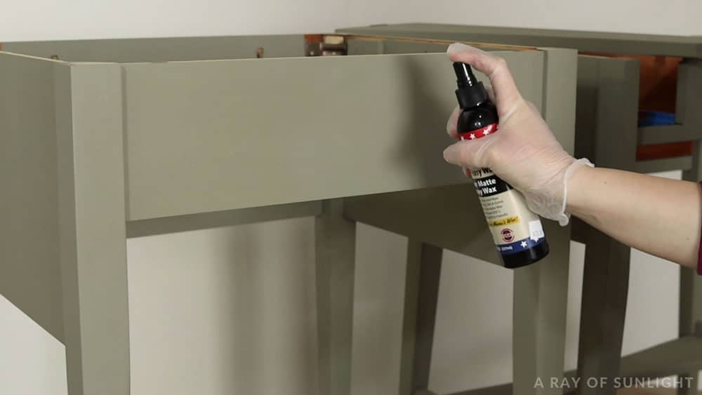 spraying easy peasy spray wax over painted table