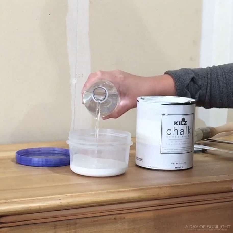 pouring water into white chalk paint to make whitewash
