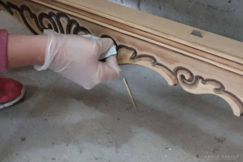 sanding the details at the bottom of the dresser with a folded up piece of sandpaper