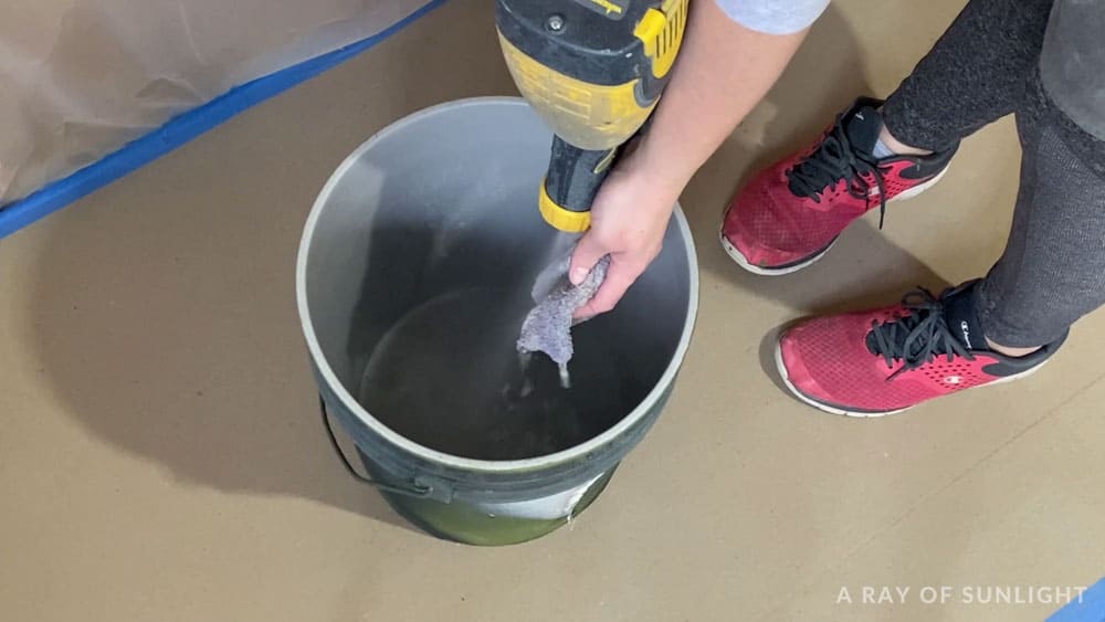 spraying warm soapy water into 5 gallon bucket
