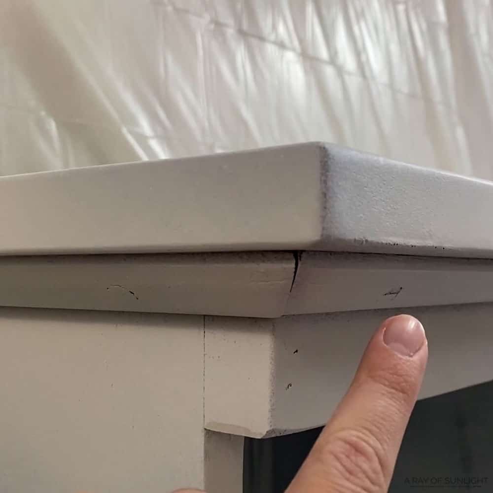 finger pointing to cracks, dings and details on primed furniture