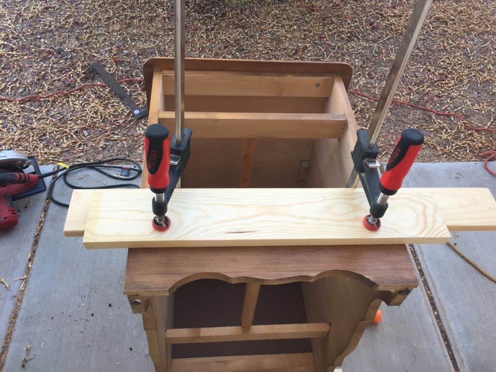 wood clamped to the bottom of the nightstand to make a straight cut with the circular saw
