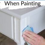 A hand sands a white-painted wood table; text reads How to Hide Wood Grain When Painting.
