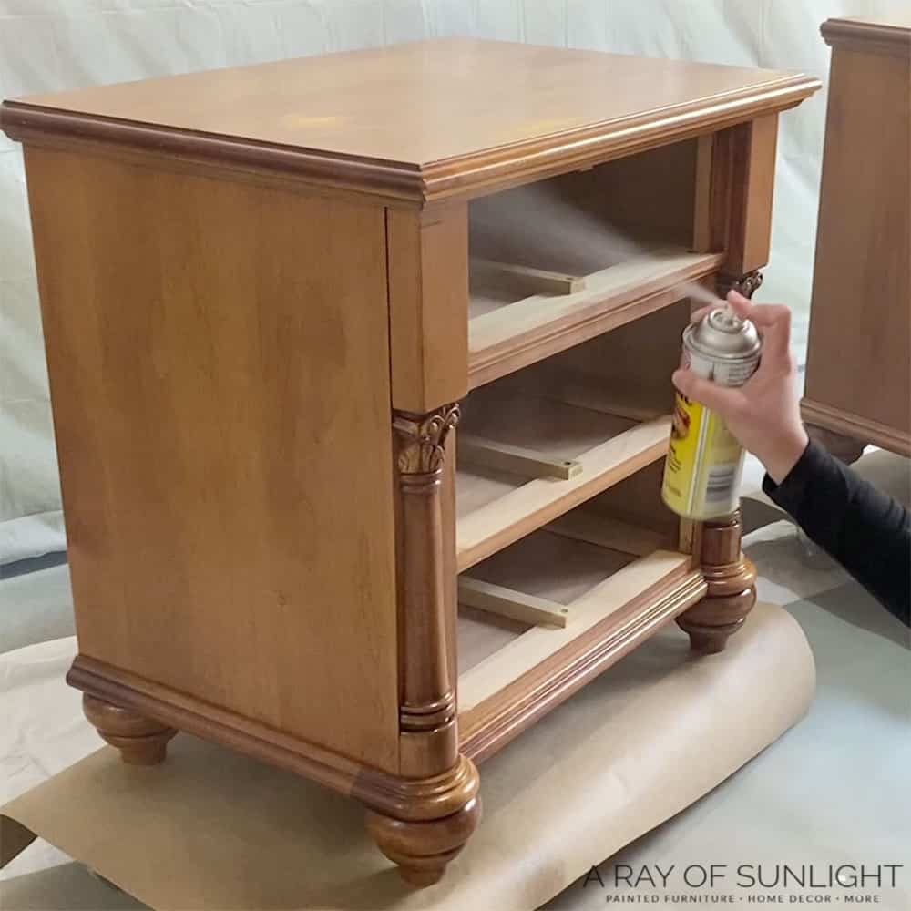 Spraying clear shellac on wood nightstand