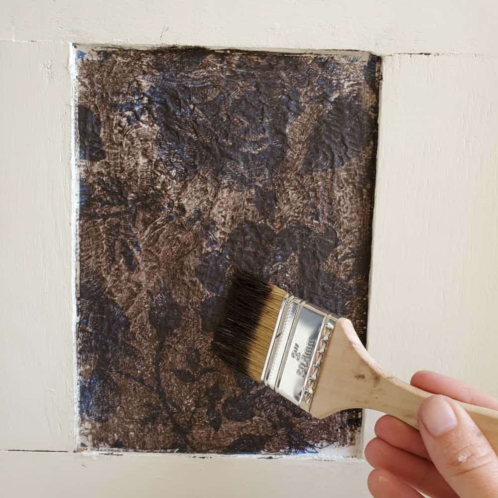 brushing brown wax onto decoupaged surface