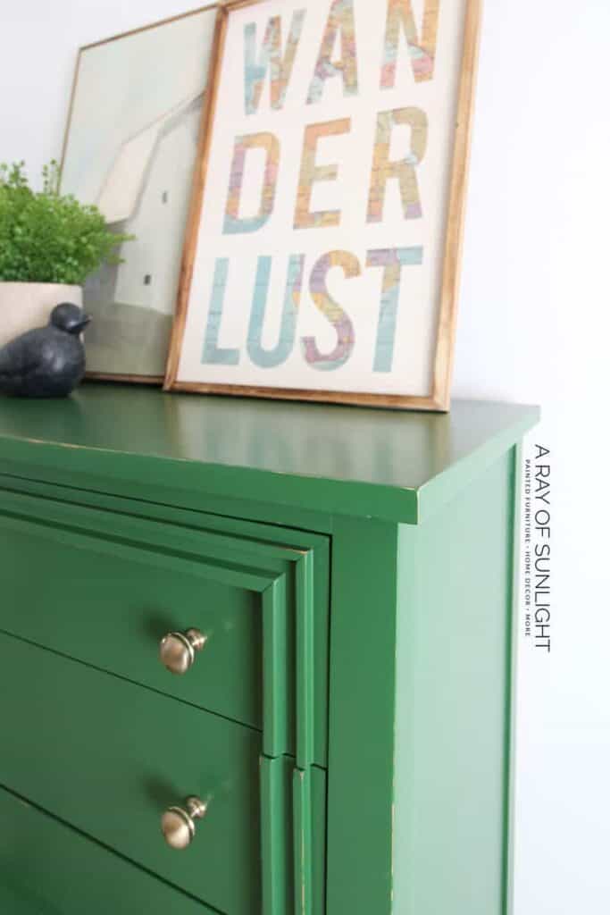 Close side view of a green painted modern dresser with gold hardware