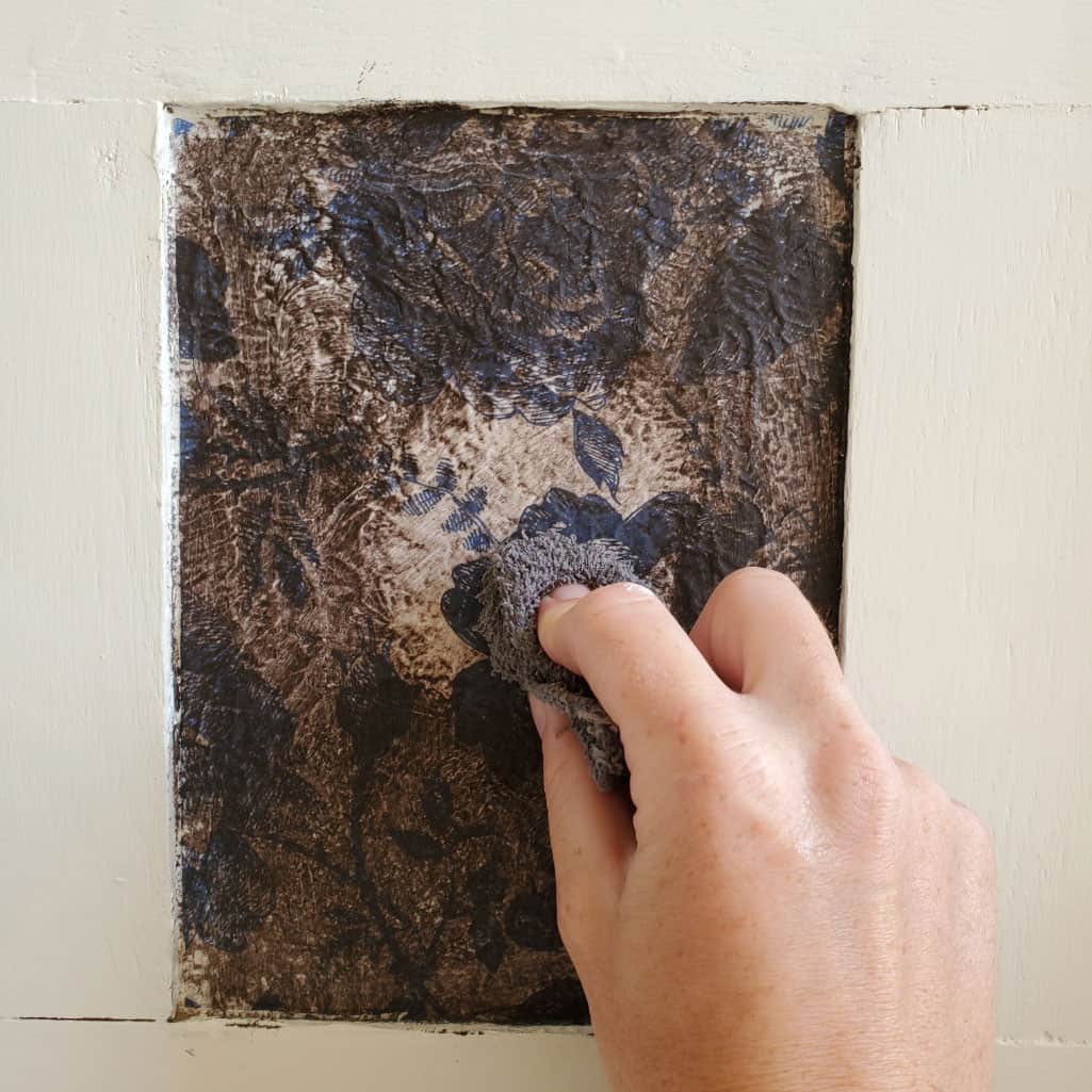 Wiping excess brown wax off decoupaged surface