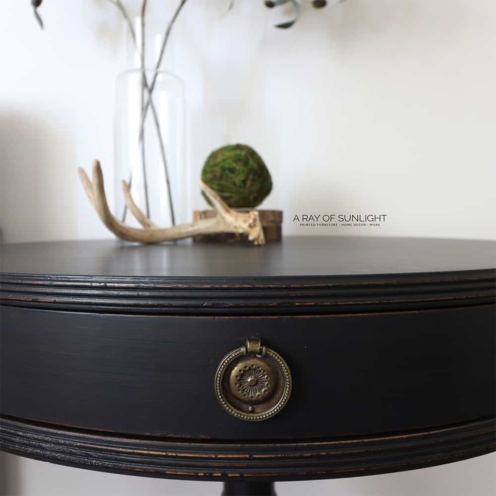 Close up of black milk painted round top nightstand