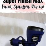 Hand holding a HomeRight Super Finish Max paint sprayer, spraying paint onto a white surface.