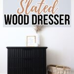 Black slatted wood dresser with decor on top, next to a woven basket, against a white wall.