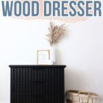 Black DIY slatted wood dresser with decor on top, next to a woven basket against a white wall.