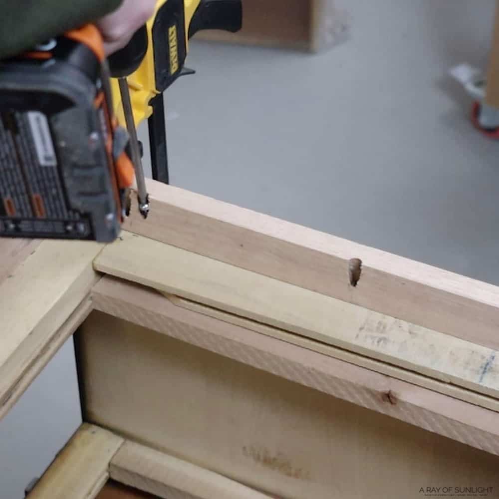 Screwing the oak wood base onto the bottom of the dresser