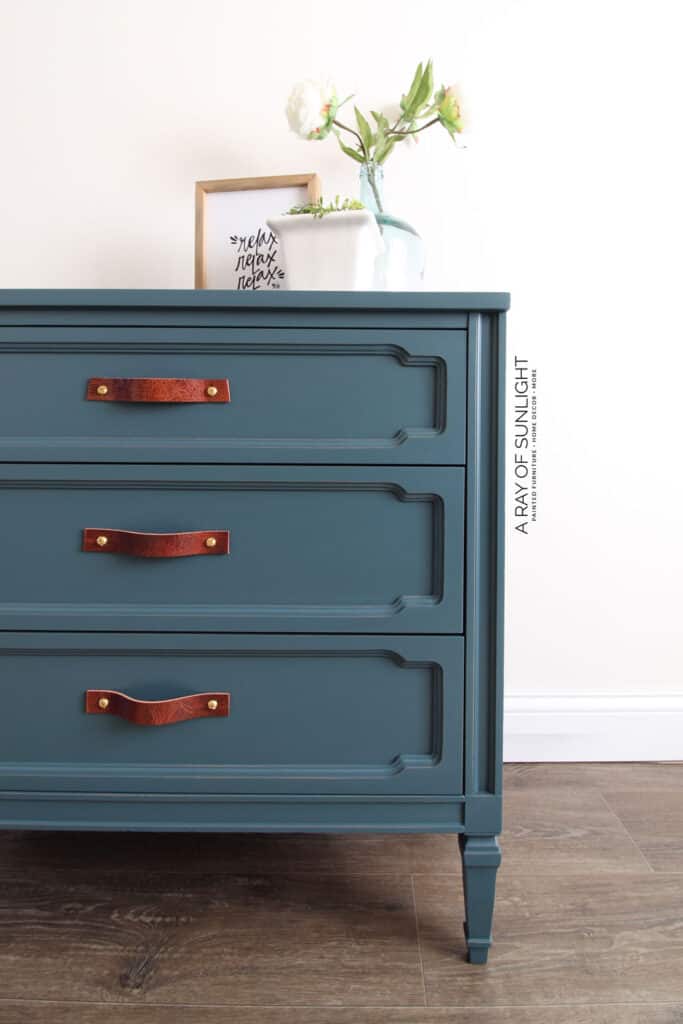 a partial photo of the dresser with teal furniture paint and the leather handles