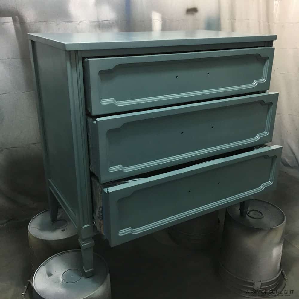 painted dresser with drawers pulled partially out while letting the paint dry