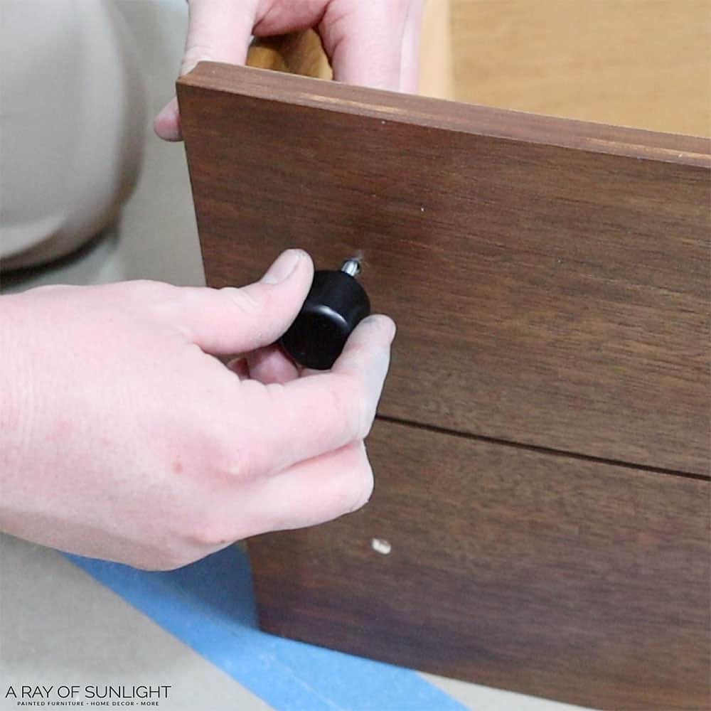 Adding new black knob hardware to the stained drawers