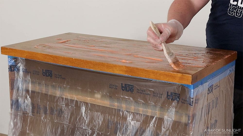 Applying Citristrip stripper to the top of a dresser with a paintbrush.