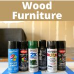 Six cans of spray paint are lined up on a table with text promoting spray painting wood furniture.