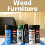 Six cans of spray paint for wood furniture are lined up on a blue and white striped surface.