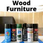 Six cans of spray paint are lined up on a blue-striped surface with text about spray painting wood furniture above them.