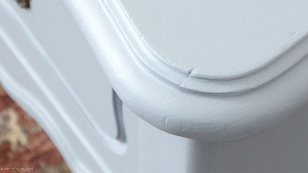 Close up view of dings and scratches in the painted end table's finish.