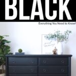 A fully black painted dresser with black knobs sits against a white wall