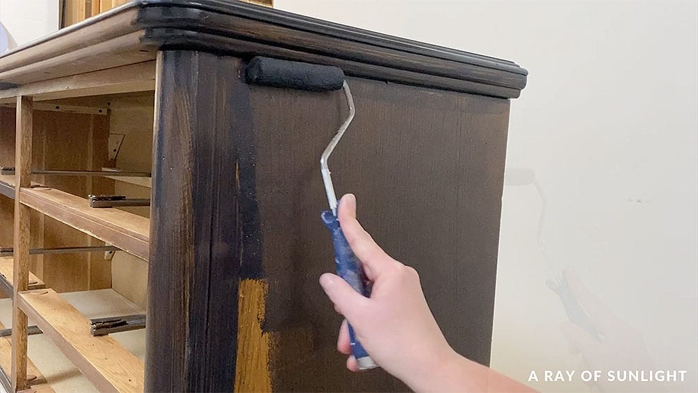 Using a mohair roller to roll the paint on one side of the dresser.