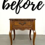 A wooden side table with curved legs under the word before in large script on a white wall.