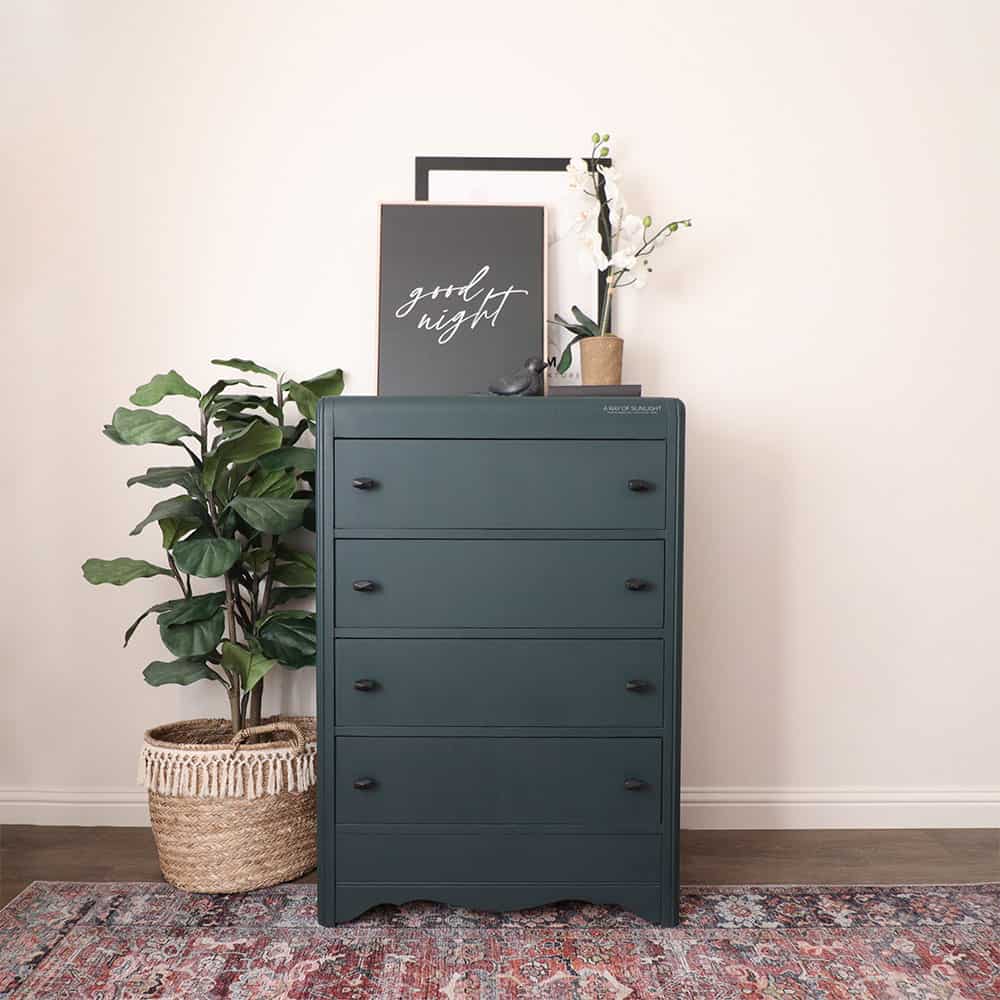 full view of blue chalk painted dresser with new black knobs, staged with boho decor
