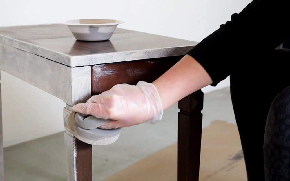 Wiping paint onto a piano bench with a true applicator sponge.