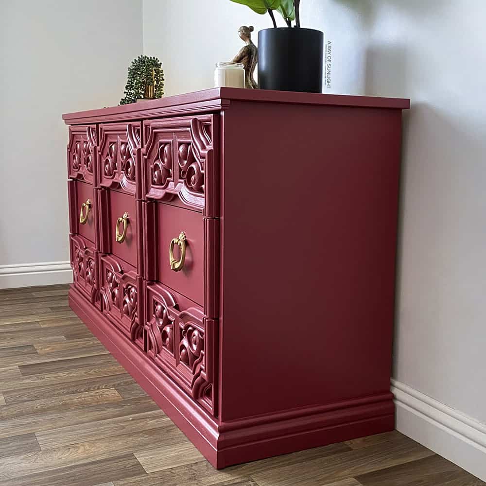 Side view of pink painted dresser with gold hardware.