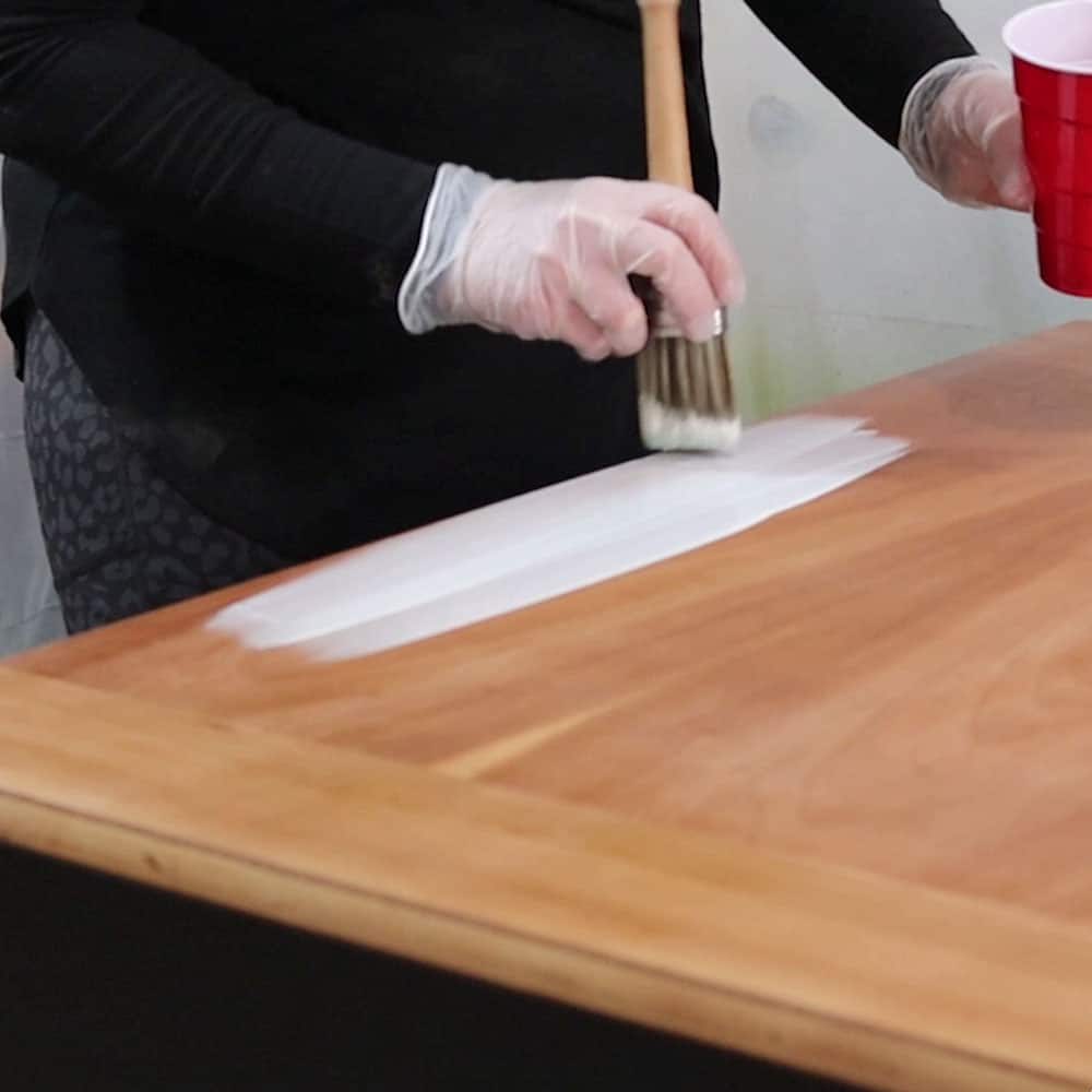 brushing whitewash on the wood coffee table top