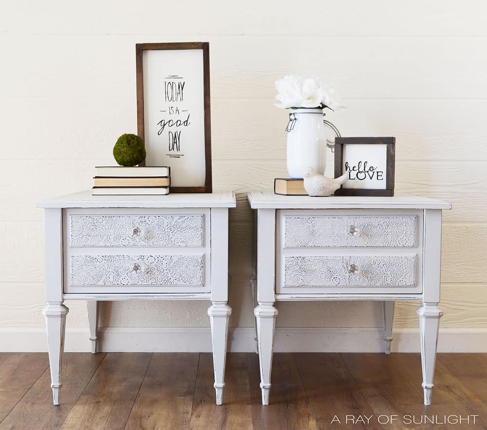 full view of light gray painted nightstands with raised stenciling on drawers