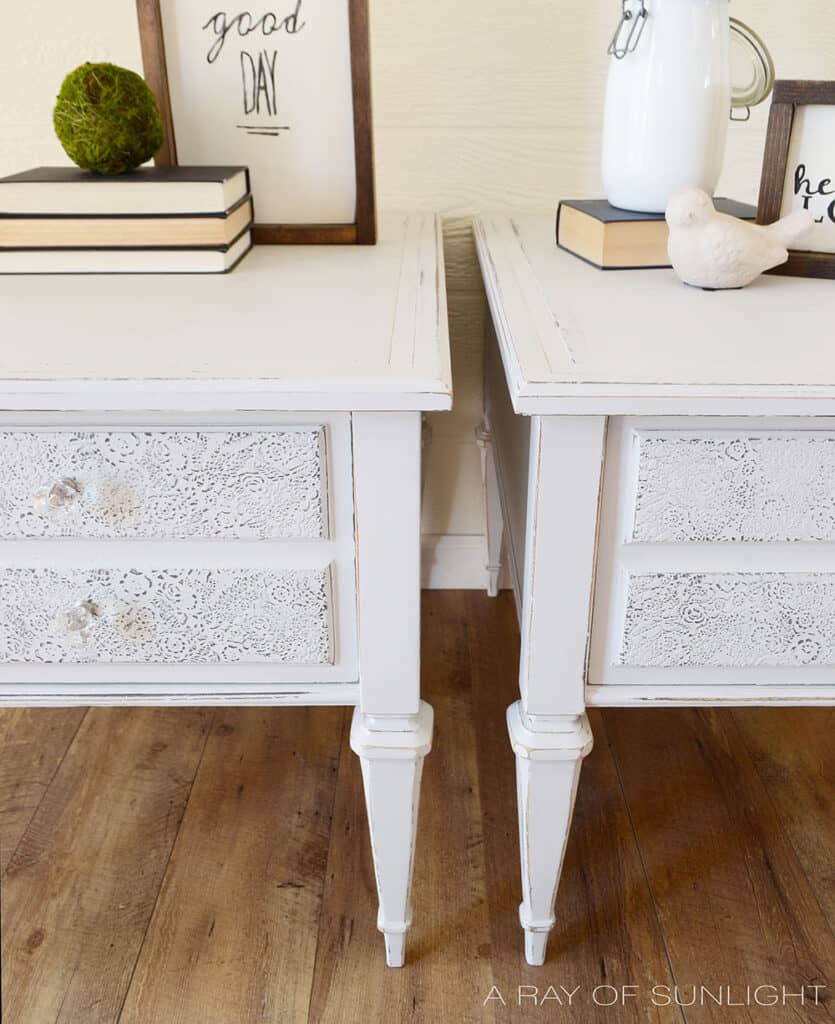 closeup of light gray painted nightstands with raised stenciling on drawers