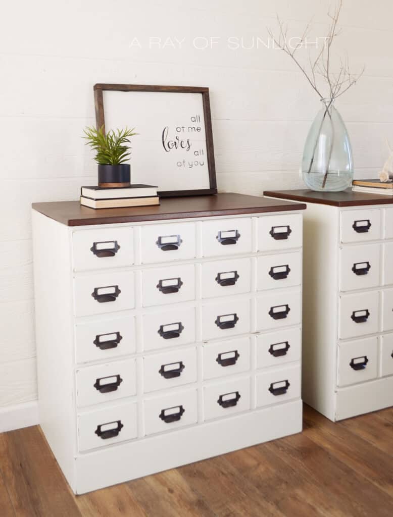 Side view of DIY card catalog style white nightstands with stained wood tops.