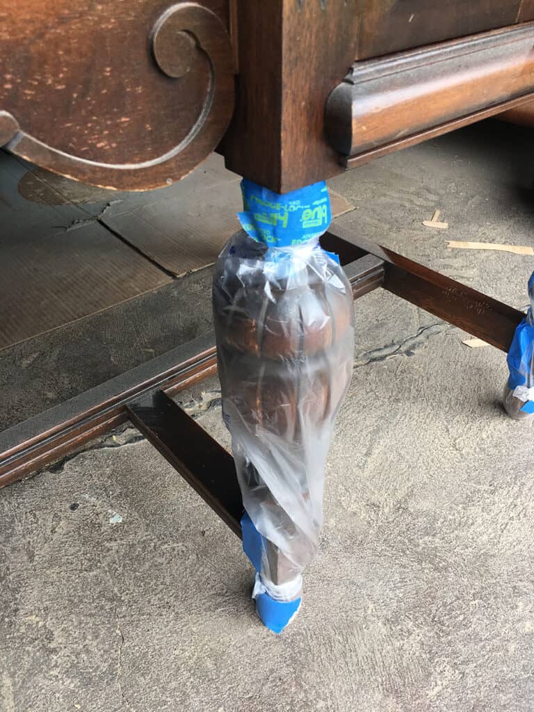 antique buffet's legs wrapped in painters tape and plastic