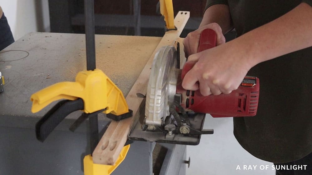 Using a circular saw to cut off the overhanging top of the cabinet.